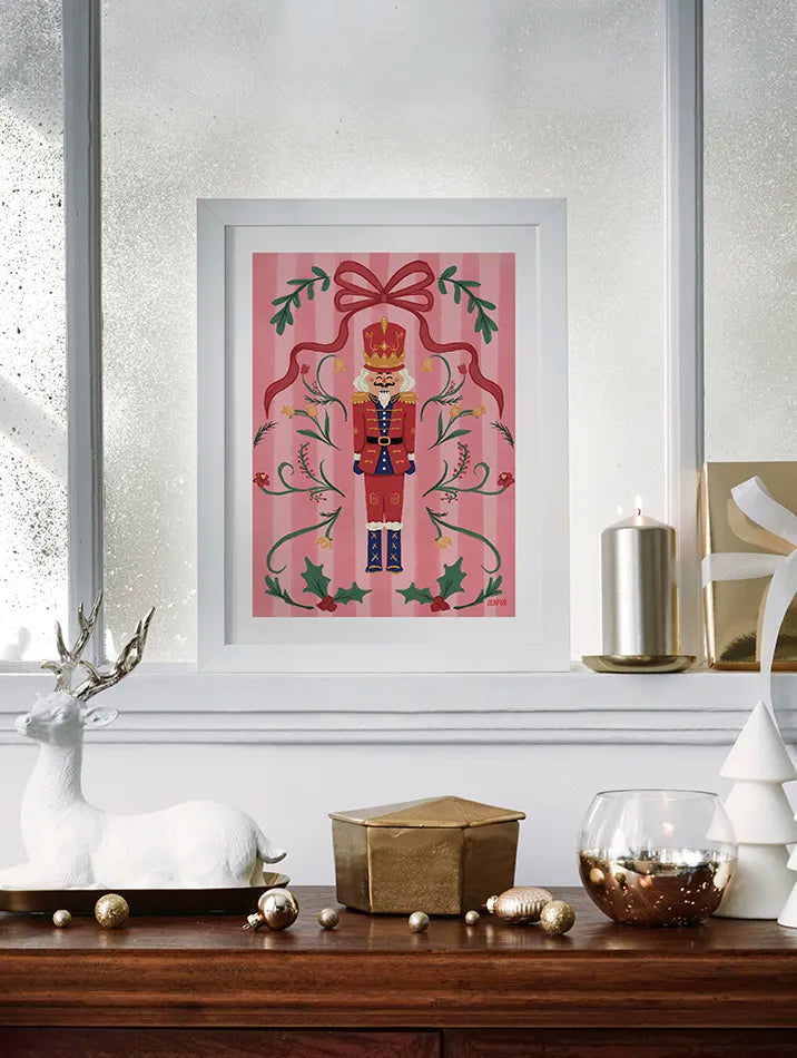 Cette affiche artistique Casse-Noisette, minutieusement illustrée par l'artiste Blanca Flor, s’inspire du ballet intemporel de Tchaïkovski pour incarner toute la féerie de Noël et l’élégance des fêtes de fin d’année. Ce design sophistiqué met en scène un soldat de Noël royal, entouré de houx luxuriants, de fleurs délicates et d’un grand nœud rouge ornemental, le tout rehaussé par une palette de tons pastels doux et harmonieux sur un fond rose.