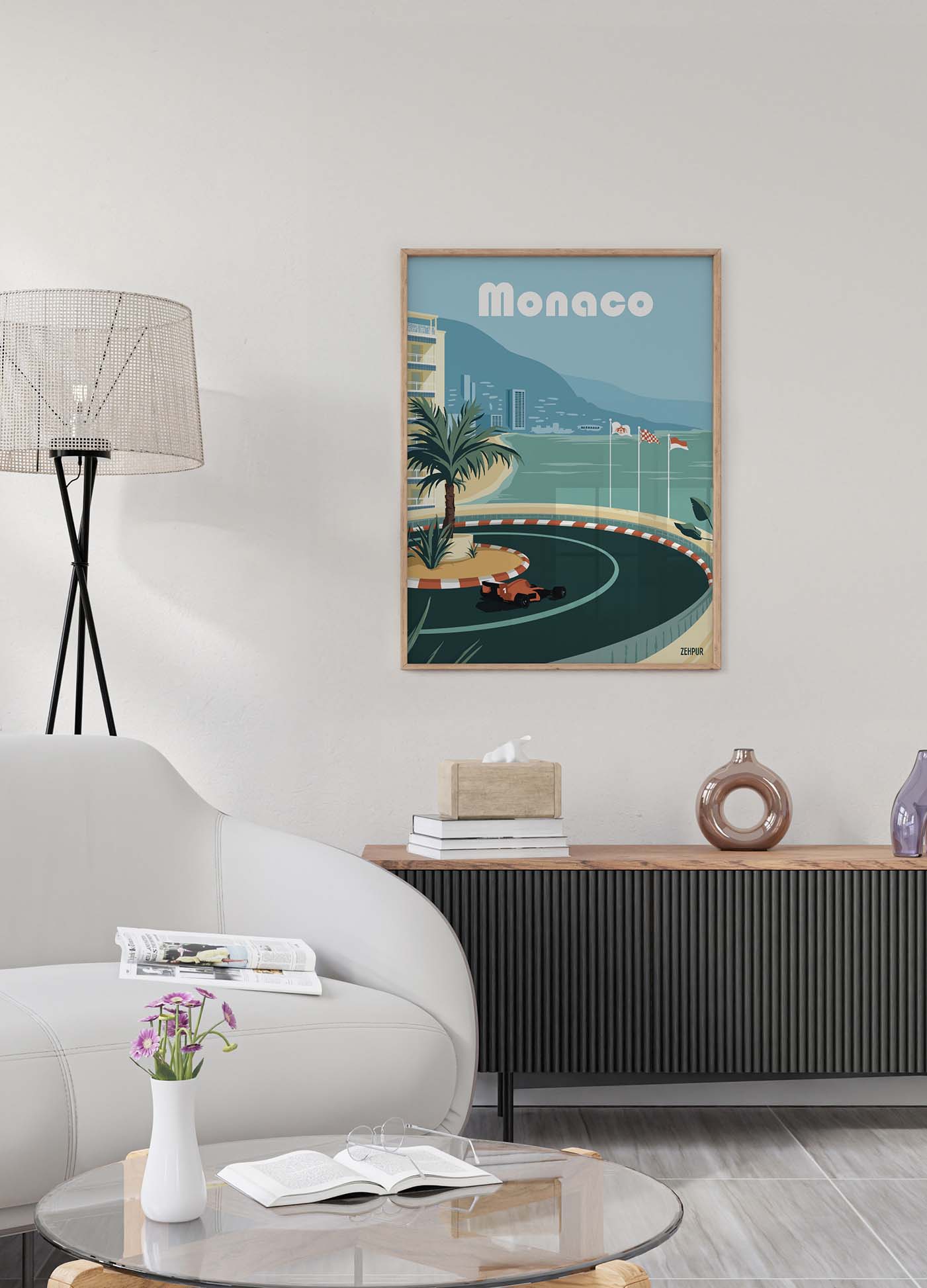 Affiche murale du Grand Prix de Monaco dans un salon moderne. L'affiche montre une voiture de course sur un circuit sinueux entouré de palmiers et de bâtiments en bord de mer, avec l'inscription 'Monaco' en haut. La scène inclut un canapé blanc, une lampe sur pied, une table basse avec des livres et un vase de fleurs, et un meuble de rangement moderne.